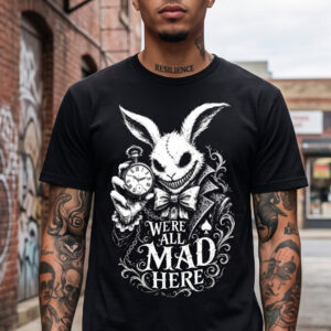 Man wearing a black T‑shirt with a white illustrated rabbit holding a pocket watch and the slogan 'We’re All Mad Here' on the front.